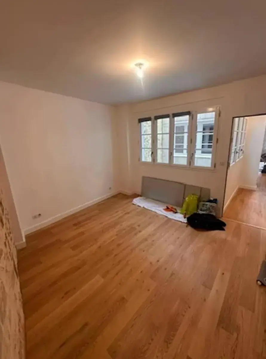 Pièce principale avant peinture : murs blancs et parquet en chêne