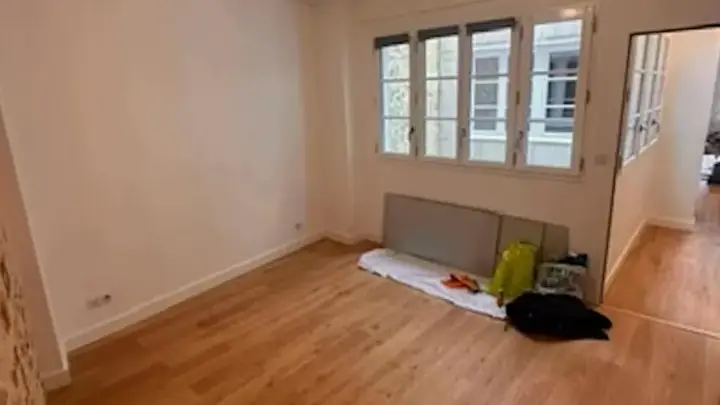 Pièce principale avant peinture : murs blancs et parquet en chêne
