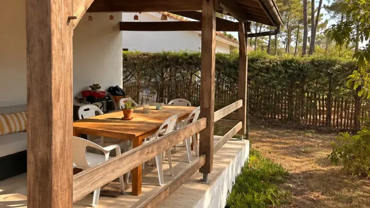 Avant les travaux, poteaux et garde-corps en bois grisé sous la terrasse couverte
