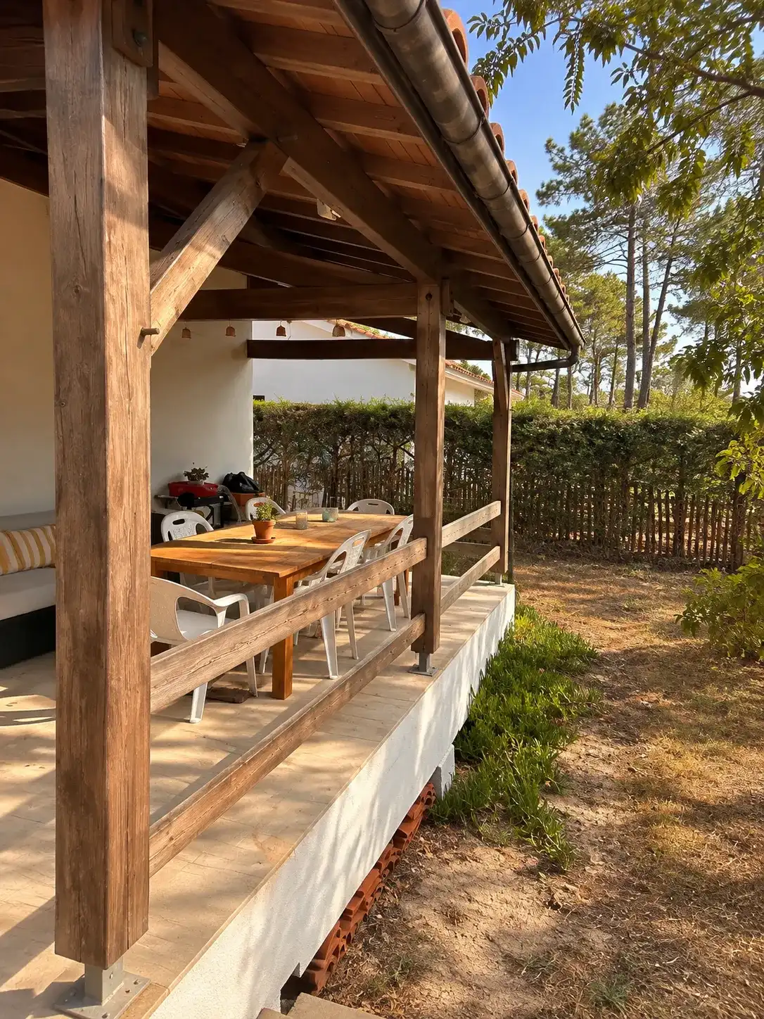 Avant les travaux, poteaux et garde-corps en bois grisé sous la terrasse couverte